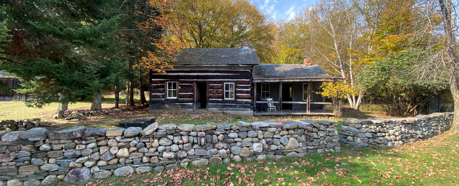 Fall picture of a dry stone stacked fence, old farmstead household, with dark logs and white grout.